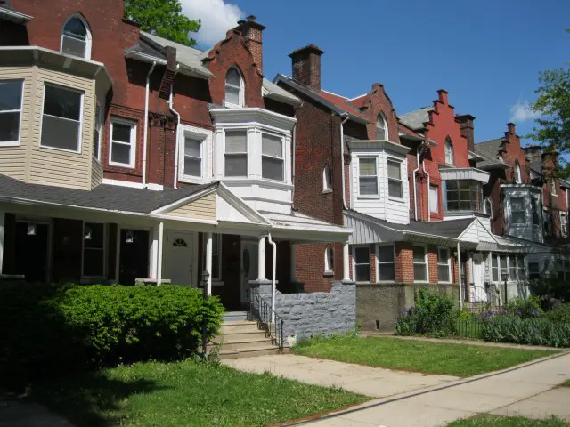 A row of houses with a sidewalk in front.