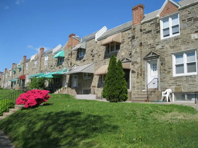 A row of brick houses with lawn chairs in front.