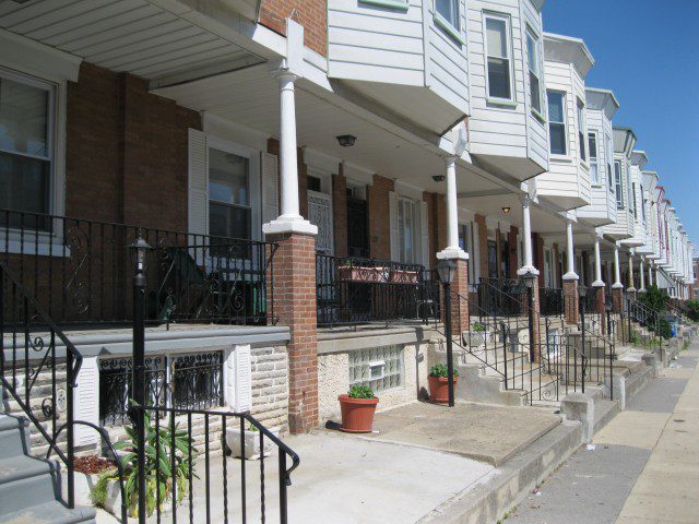 A row of houses with white pillars and red brick.