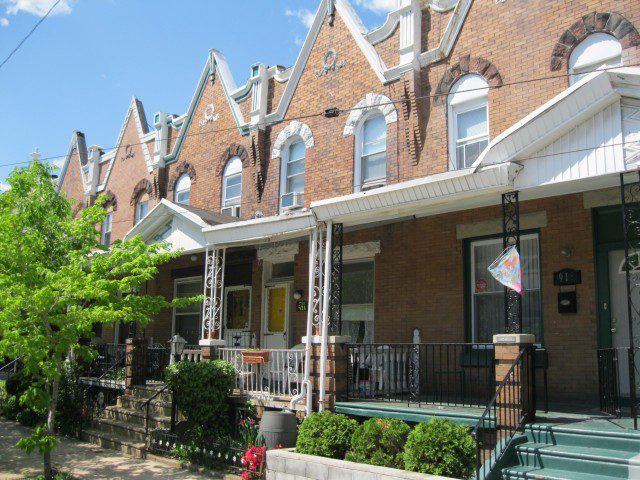 A row of brick houses with a porch and steps.