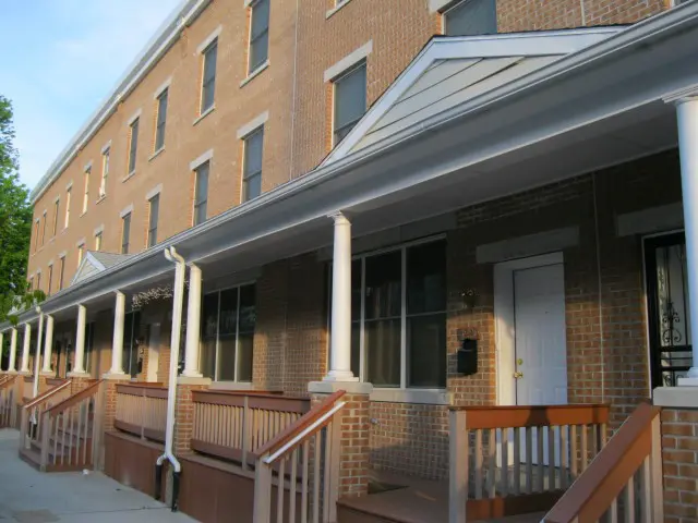 A row of brick buildings with a porch and steps.