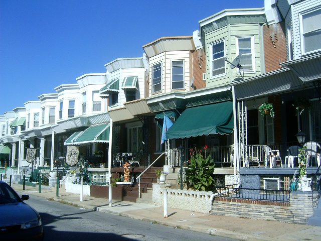 A row of houses with awnings on the side.