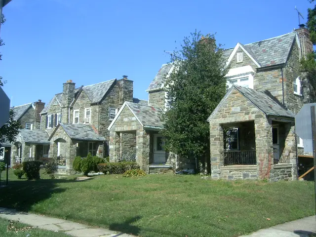 A row of houses with stone facades and a tree.