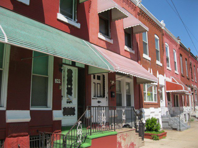 A row of houses with green awnings and red walls.
