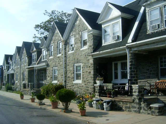 A row of houses with stone facades and potted plants.